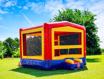 A colorful inflatable bounce house set up on a grassy field under a blue sky.