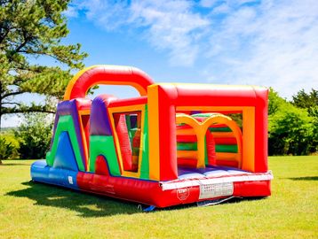 A colorful inflatable obstacle course set up on a grassy field under a blue sky.