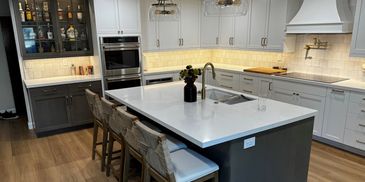 Modern kitchen with a large island, white countertops, and mixed cabinetry.