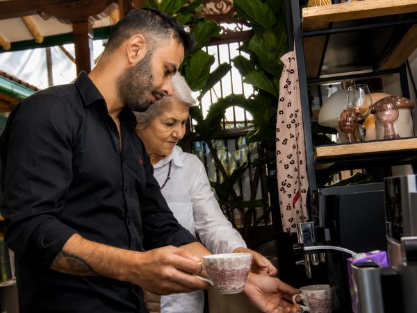 A young man and elderly woman making coffee together.