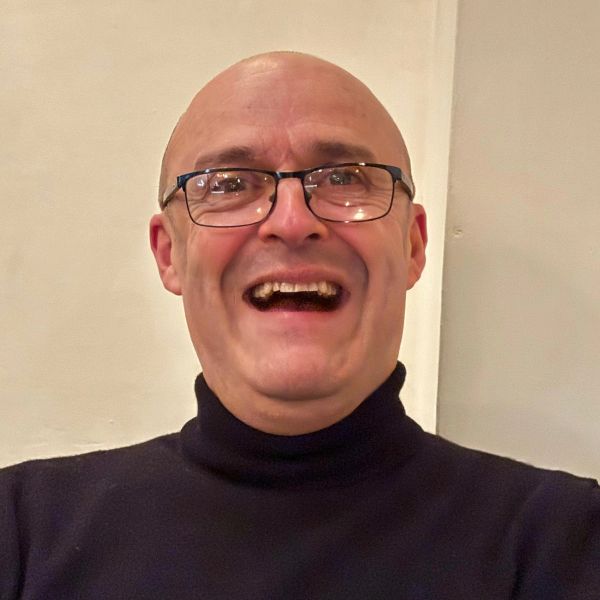 Smiling man wearing glasses and a black turtleneck.