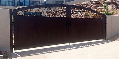 Custom Gates - Stairways LLC - Modern dark gate with lattice top at a driveway entrance.
