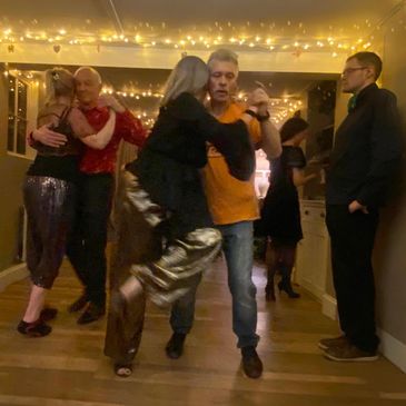 Couples dancing under string lights in a cozy room.