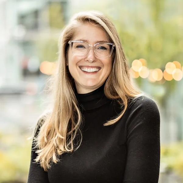 Smiling woman with glasses and long blonde hair wearing a black turtleneck.