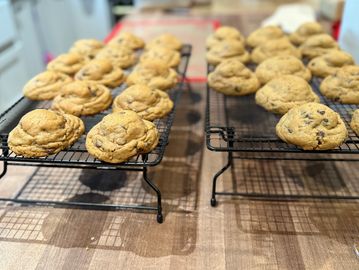 Freshly baked chocolate chip cookies cooling on wire racks.