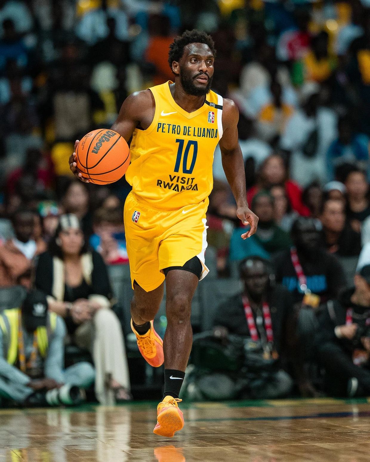 Basketball player in yellow jersey dribbling the ball on court.