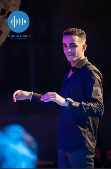 Young man in black shirt on stage with Track Band logo.