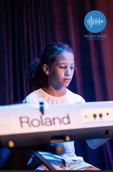 Young girl focused playing Roland keyboard on stage.