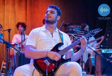 Musician playing electric guitar on stage during a live performance.