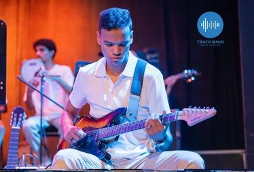 Young man focused on playing electric guitar during a live performance.