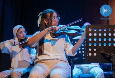 Two women playing violins in a music performance setting.