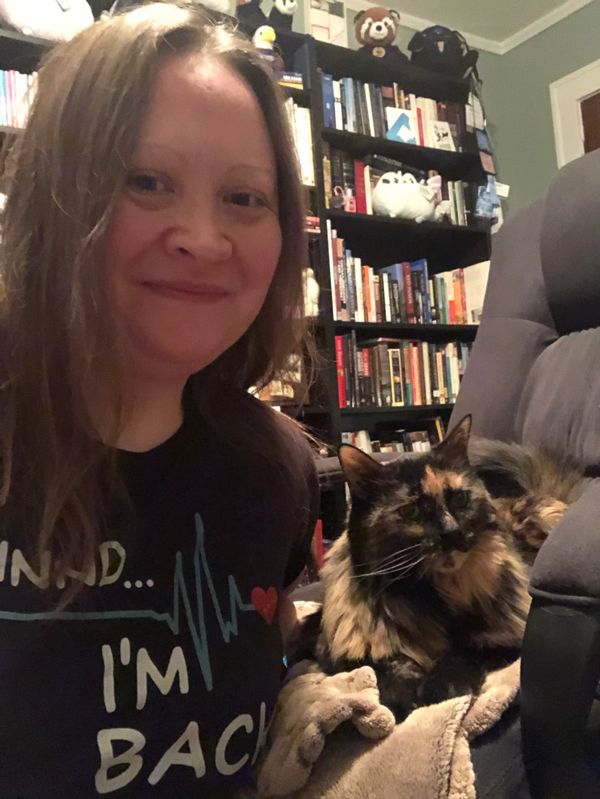 Brilliant poet and author April McCloud sits in her library with long-haired tortie cat, Inari. 