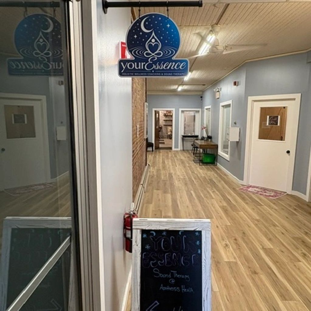 A calm wellness center hallway with wooden floor and sign.