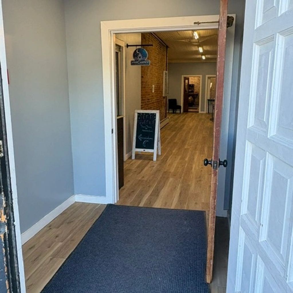Open door leading to a hallway with wooden flooring.