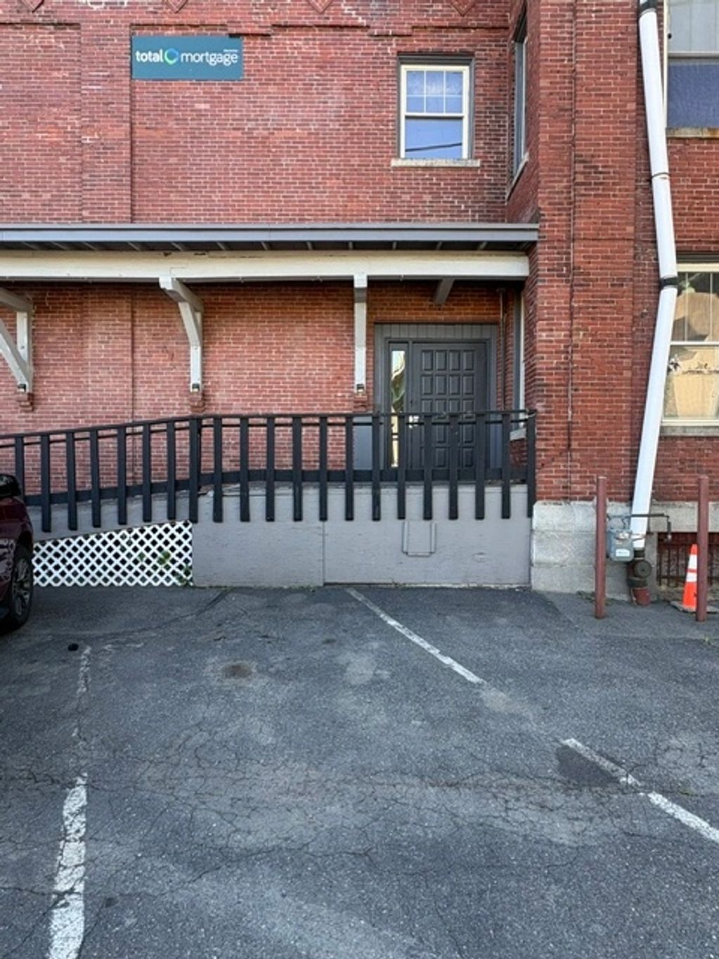 Brick building entrance with a ramp and parking spaces.