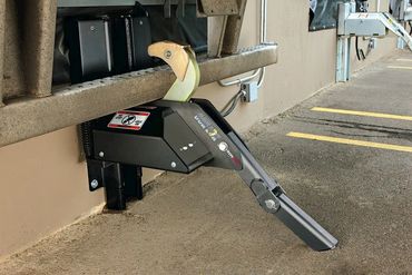 Parking lock device installed on asphalt near a building wall.