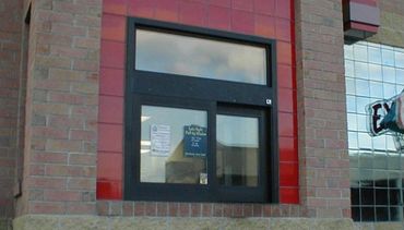 A drive-thru window on a brick building with red tiles.