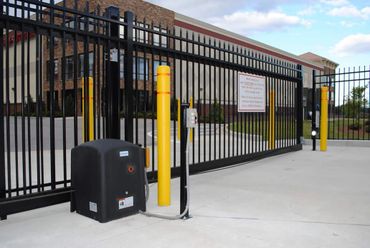 Automated sliding security gate with yellow safety bollards at commercial entrance.