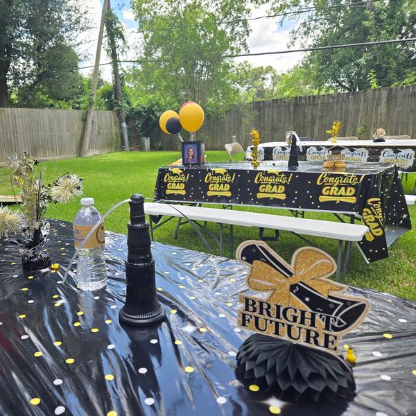 Outdoor graduation party setup with black and gold decor.