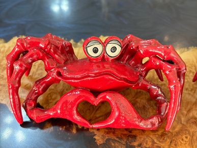 Handcrafted, red, ceramic crab sculpture with heart shaped detail featuring vibrant iridescent, raku