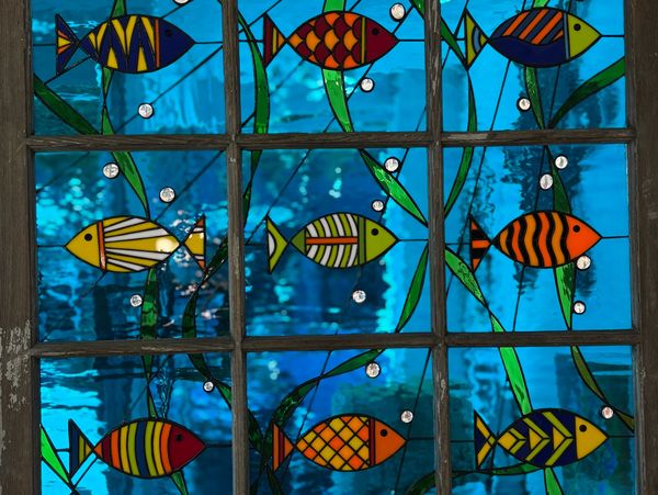 Stained glass window by Richard Currie featuring colorful fish and aquatic plants, handcrafted with