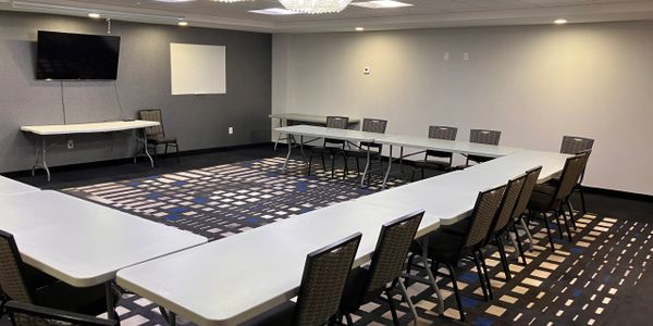 Conference room with U-shaped tables and chairs arranged for a meeting.