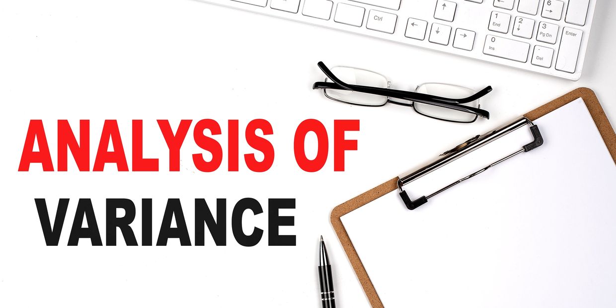 Workspace with 'Analysis of Variance' text, clipboard, pen, glasses, and keyboard.