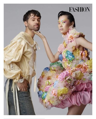 Two models showcase avant-garde fashion with floral and ruffled designs against a plain backdrop.
