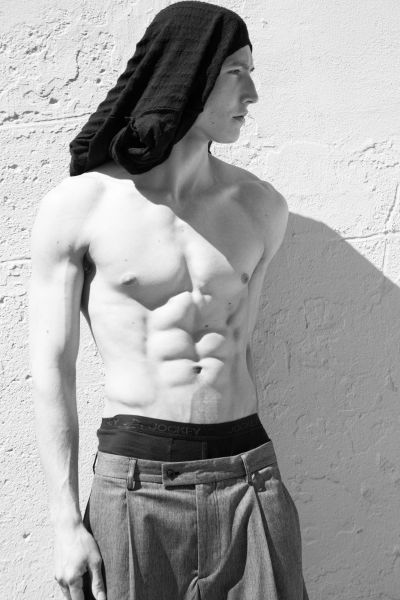 Shirtless man with a towel on his head looking to the side.