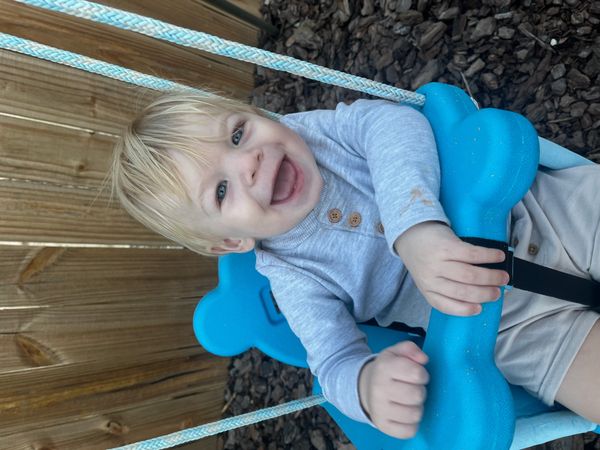 Smiling toddler on a blue swing.