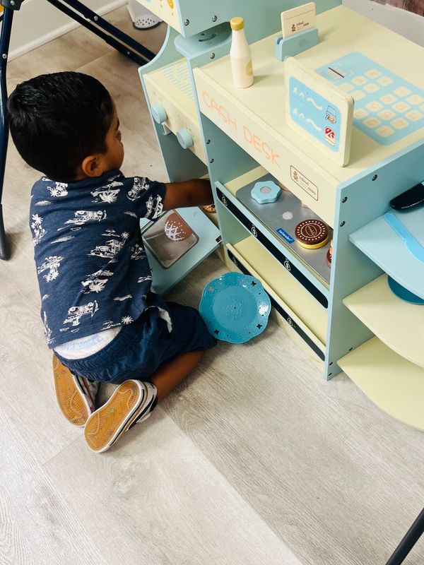 Child playing with a toy kitchen cash desk.