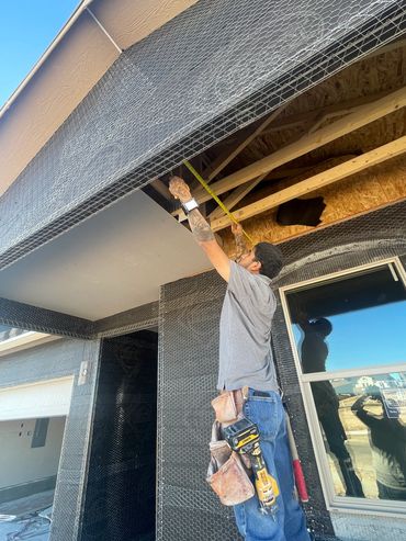 Construction worker measures ceiling framework on a building site.