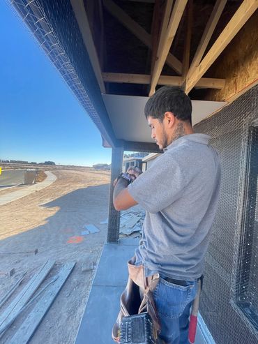 Construction worker checking his watch on a building site under a clear sky.
