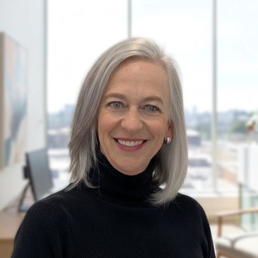 Smiling woman with gray hair in a black turtleneck.