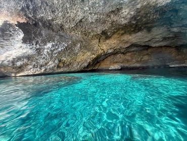 Crystal-clear turquoise water inside a rocky sea cave.
