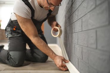 The image shows a person, likely a professional or DIY enthusiast in the process of preparing a room