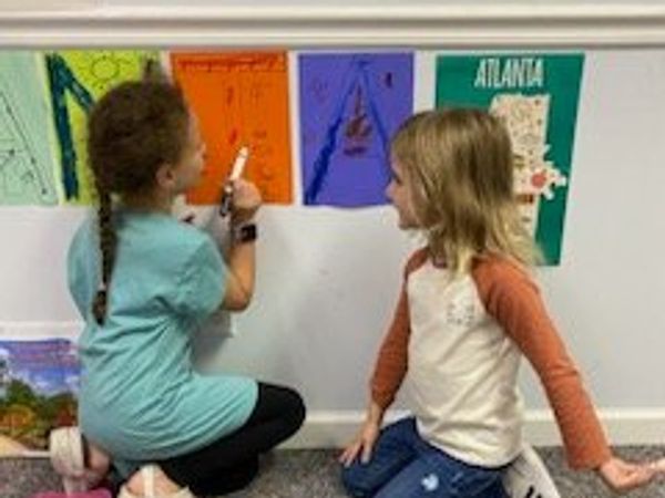 Two children writing on a wall with colorful papers.