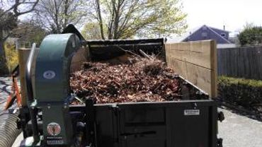 A large wood chipper machine filled with dry leaves outdoors.
