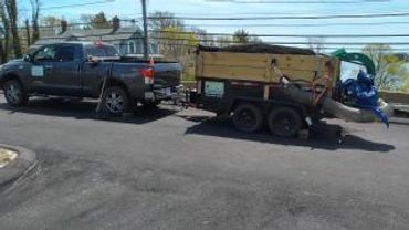 Pickup truck towing a loaded utility trailer on a residential street.