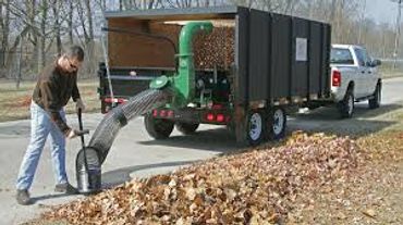 Man using a leaf vacuum machine to collect fallen leaves.