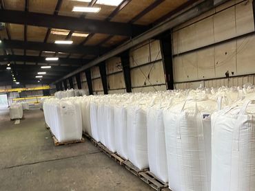 Large white bags stacked on pallets in a spacious warehouse.