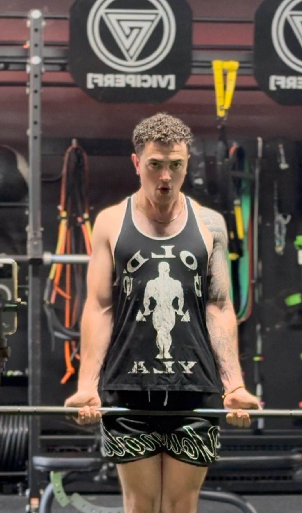 Man lifting a barbell in a gym, focused and determined.