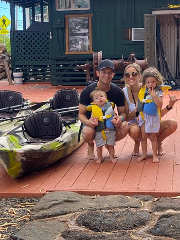 A young couple with two young children in life jackets getting ready to go kayaking