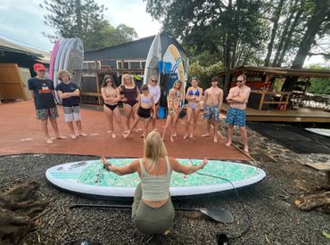 A female SUP instructor giving a paddleboard lesson to paddle board tour group