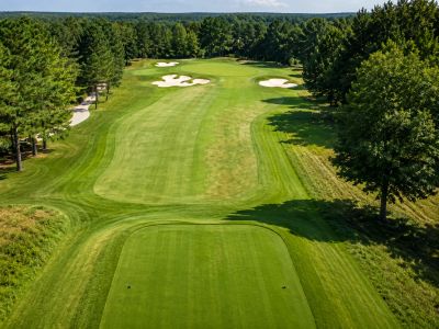 Golf course fairway and teeing area with managed turf, trees, and sand bunkers.