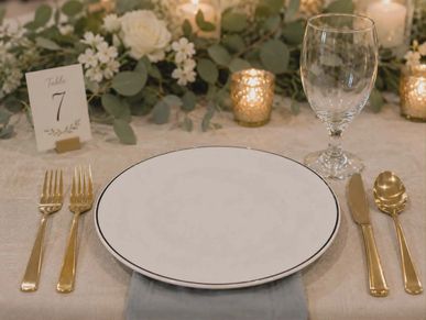 Elegant table setting with gold cutlery and floral centerpiece.