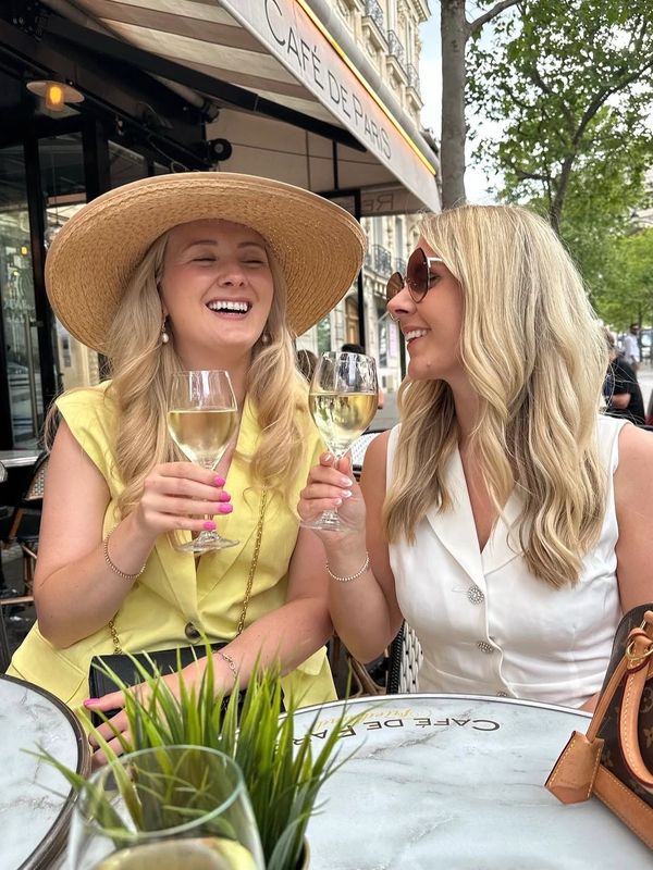 Two women enjoying white wine at an outdoor café in Paris.