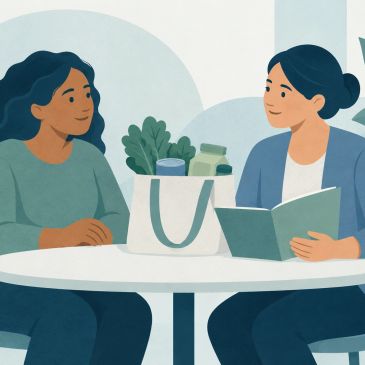 Two women having a conversation at a table with groceries.