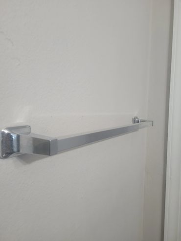Empty metallic towel rack mounted on a plain white wall.