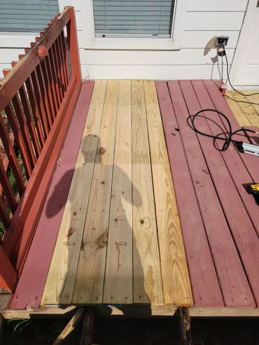 Partially replaced wooden deck with new boards in the middle.